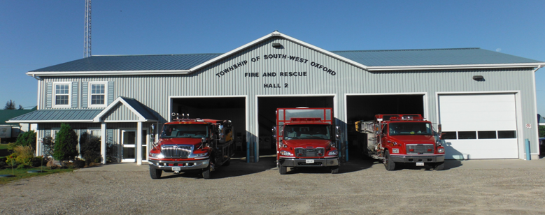 Fire station located in Mount Elgin, building and 3 fire engines inside of a building