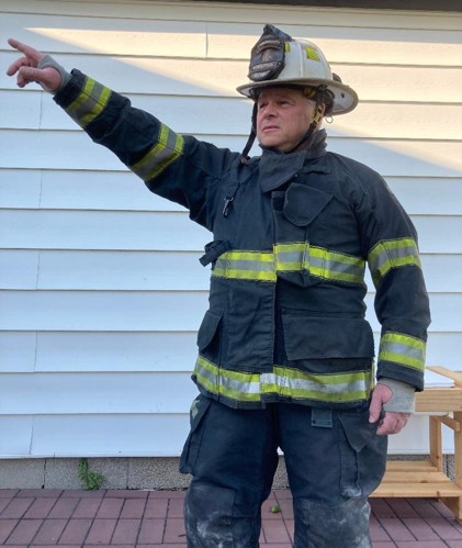 District Chief Dave Mitchell in his fire fighter uniform pointing with his right arm during a training exercise